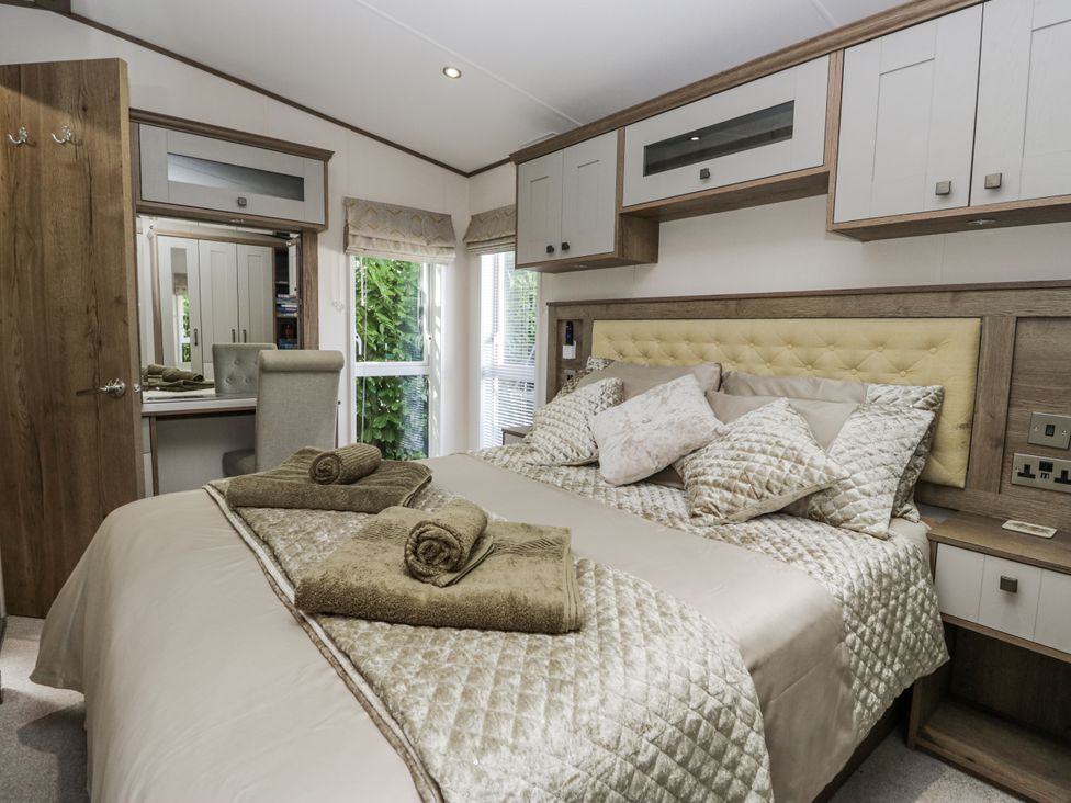 A bedroom with a bed and chair at Lilac Lodge Carnforth