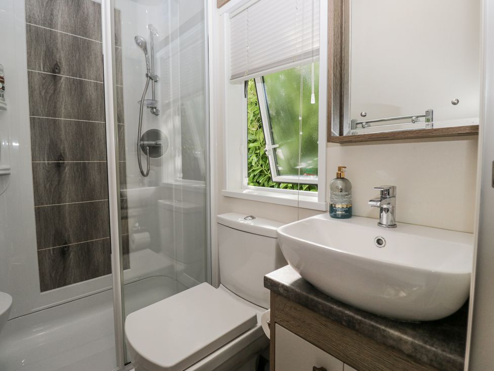 A bathroom featuring a shower, toilet, and sink at Lilac Lodge in Carnforth