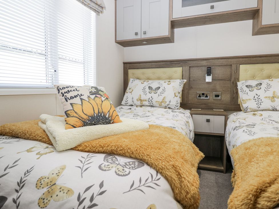 A bedroom with two beds and a window at Lilac Lodge in Carnforth