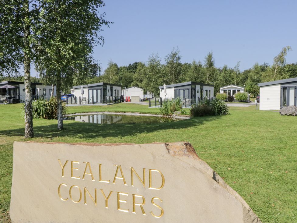 An outdoor area with a lodge and a pond at Yealand Conyers in Carnforth