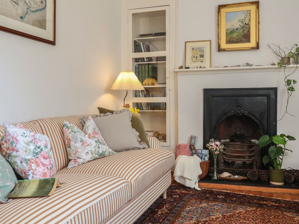 A living room with a striped sofa and bookshelf at Blackbird Cottage Northam