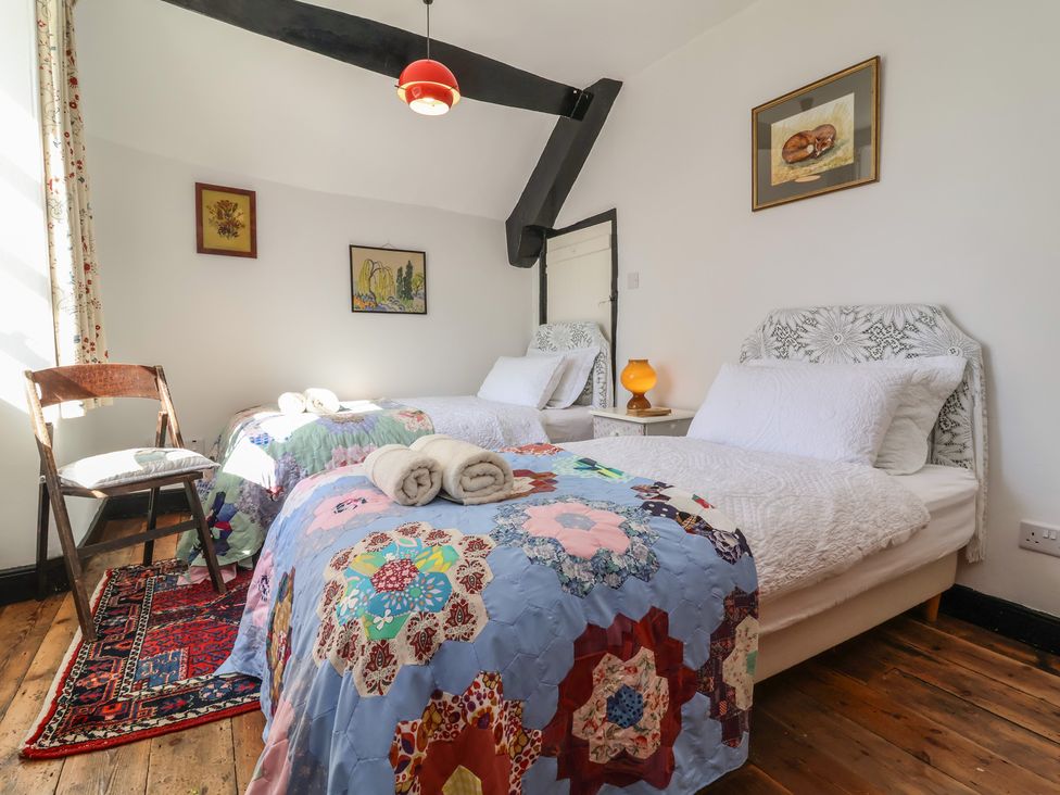 A bedroom with two beds and a chair at Blackbird Cottage Northam