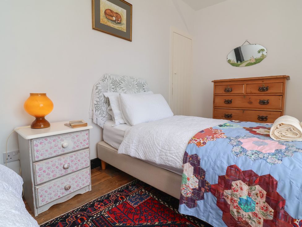 A bedroom with a bed and nightstand in Blackbird Cottage, Northam