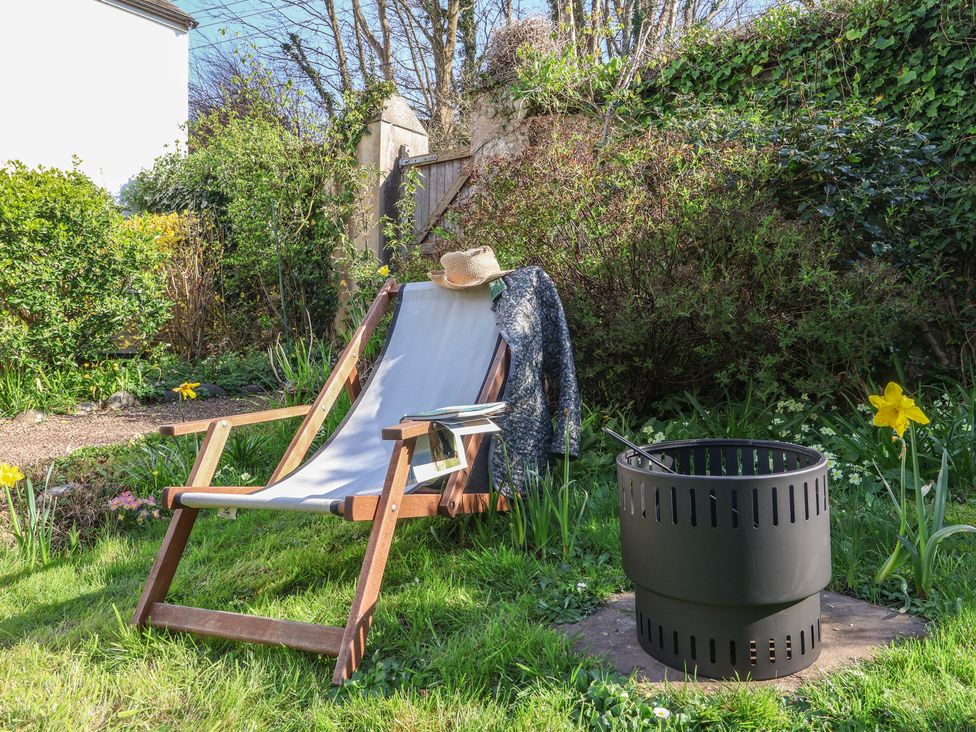 A garden with a deck chair and a fire pit at Blackbird Cottage Northam