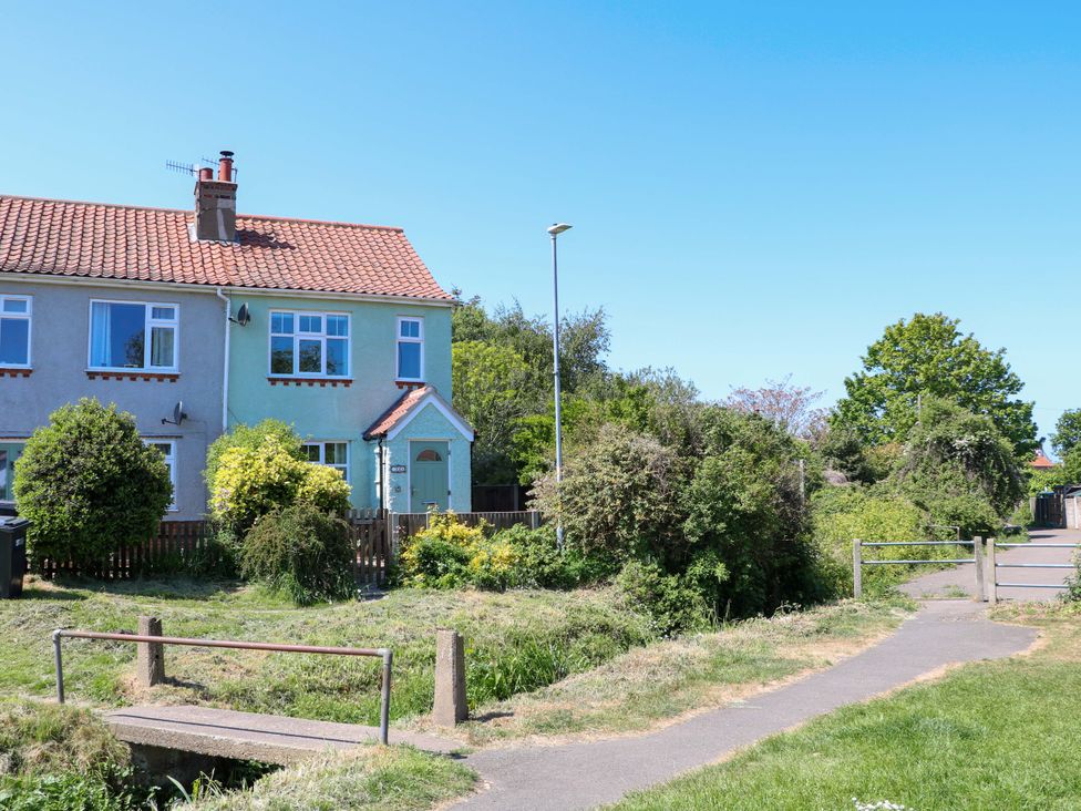 A semi detached house with a small garden and a path with a footbridge in front of it at Beck View in Sheringham