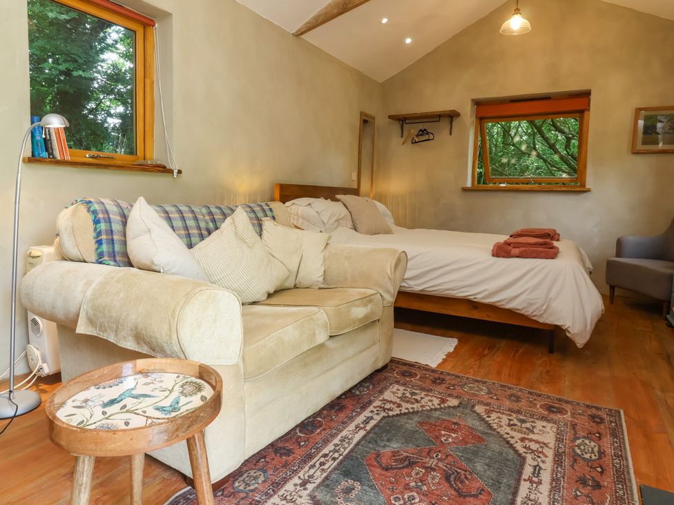 A bedroom with a bed and sofa at Brambly Cabin in Crediton
