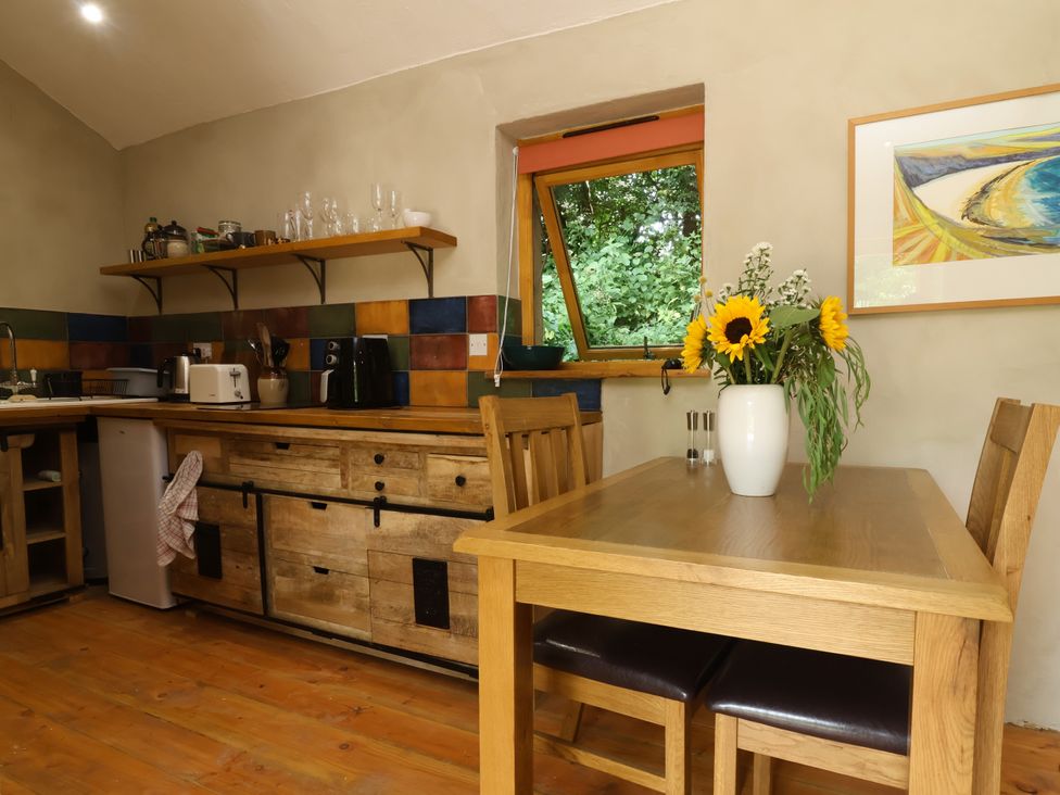 A kitchen with wooden furniture and flowers at Brambly Cabin in Crediton