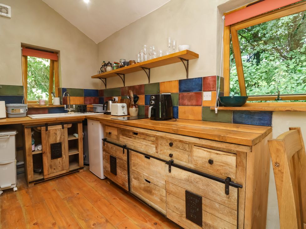 A kitchen with wooden cabinetry and appliances at Brambly Cabin in Crediton