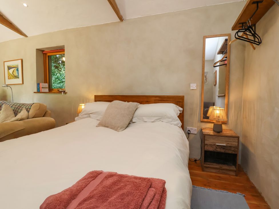 A bedroom with a bed and mirror at Brambly Cabin in Crediton