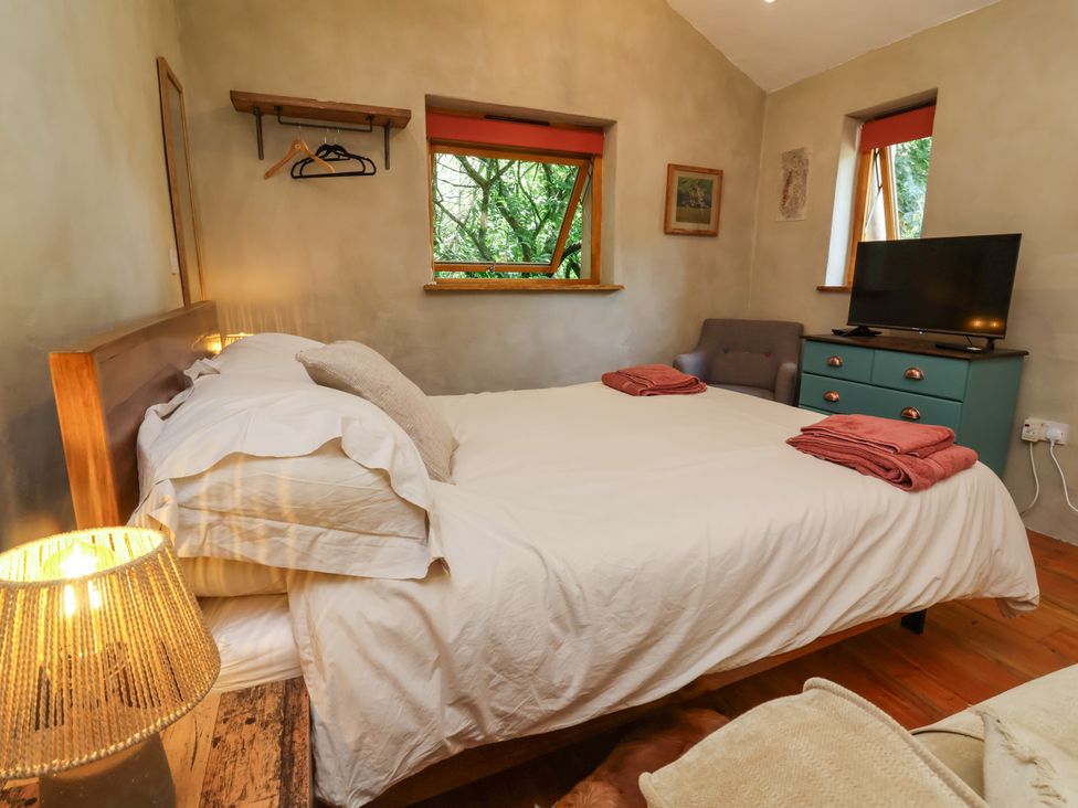 A bedroom with a bed, chair, and television at Brambly Cabin in Crediton