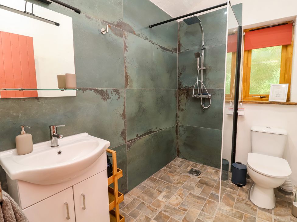 A bathroom with a shower, sink and toilet at Brambly Cabin in Crediton