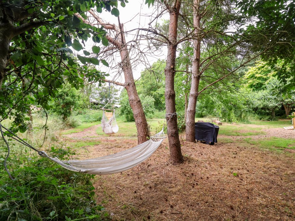 A garden with a hammock and grill at Brambly Cabin in Crediton