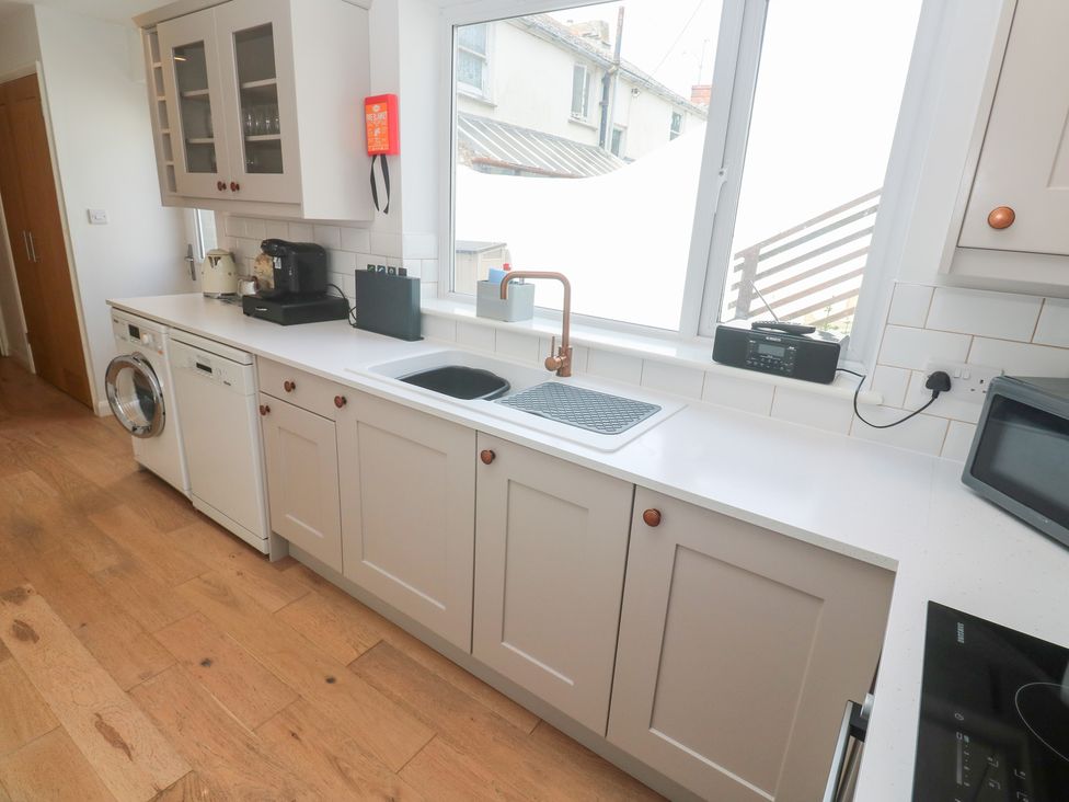 A kitchen with cabinets and appliances at Foundry Cottage In Hayle Harbour, Hayle