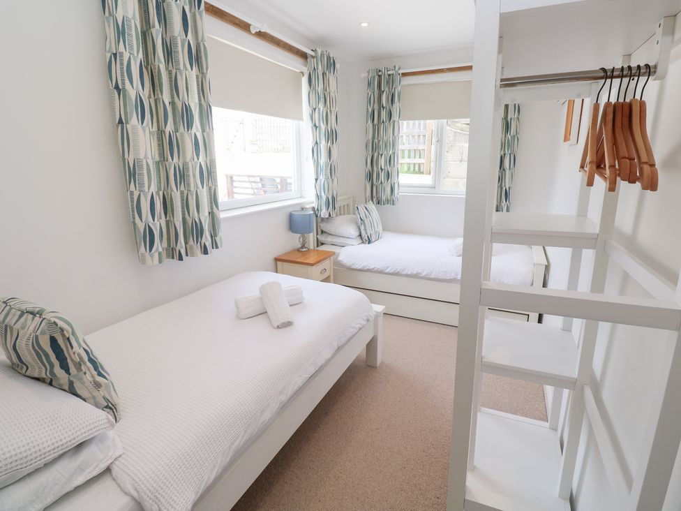 A bedroom with two beds and a side table at Foundry Cottage In Hayle Harbour, Hayle