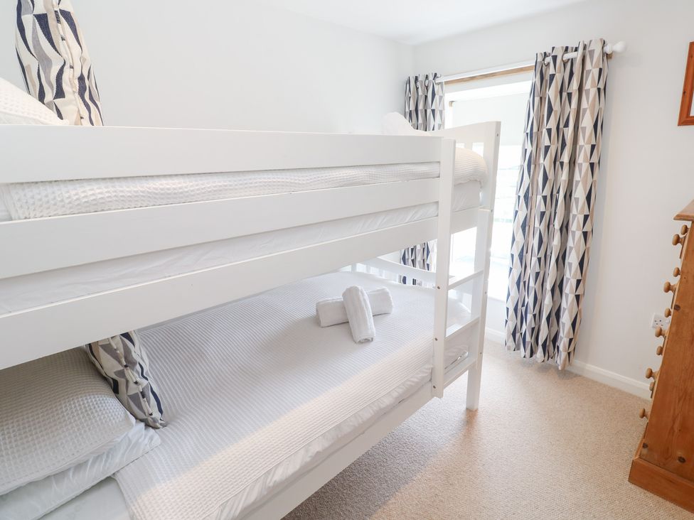 A bedroom with a bunk bed and curtains at Foundry Cottage In Hayle Harbour, Hayle