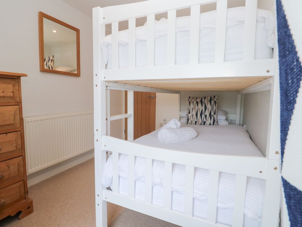 A bedroom with a bunk bed and a mirror at Foundry Cottage In Hayle Harbour, Hayle
