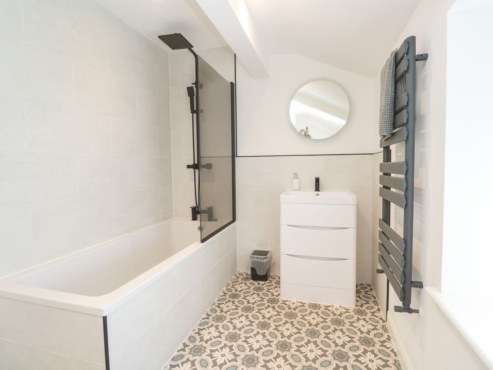 A bathroom with a bathtub, shower screen and sink at Foundry Cottage In Hayle Harbour, Hayle