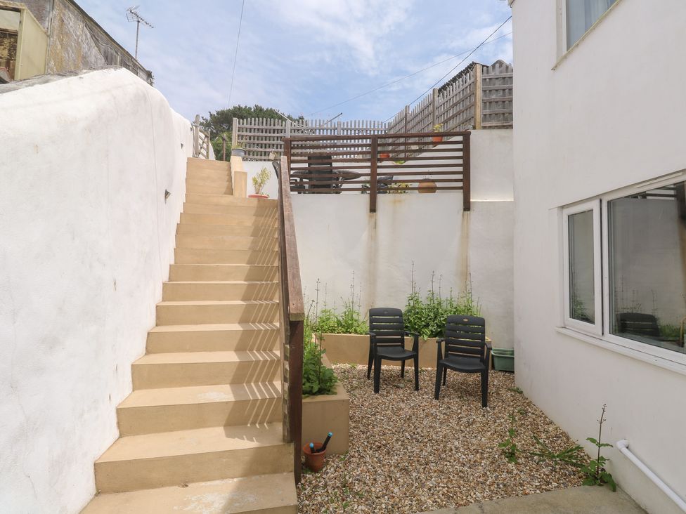 A garden with gravel, chairs, and stairs at Foundry Cottage In Hayle Harbour, Hayle