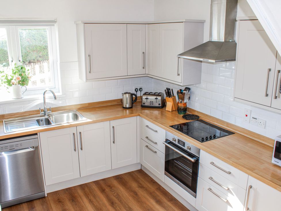 A kitchen with a sink, kettle, toaster, and cooktop at Waders in Salcombe
