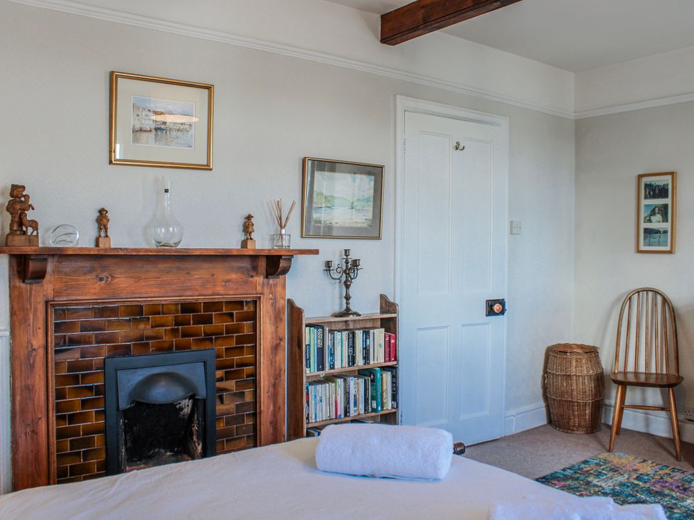 A bedroom with a fireplace and bookshelf at Waders in Salcombe