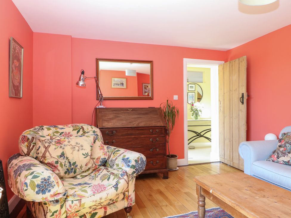 A living room with an armchair and wooden table at Cherry Garden Cottage in Sandhurst