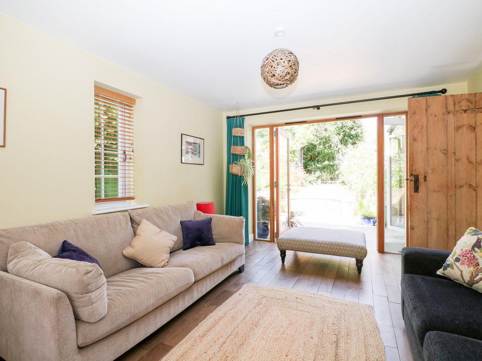 A living room with a sofa and ottoman at Cherry Garden Cottage in Sandhurst
