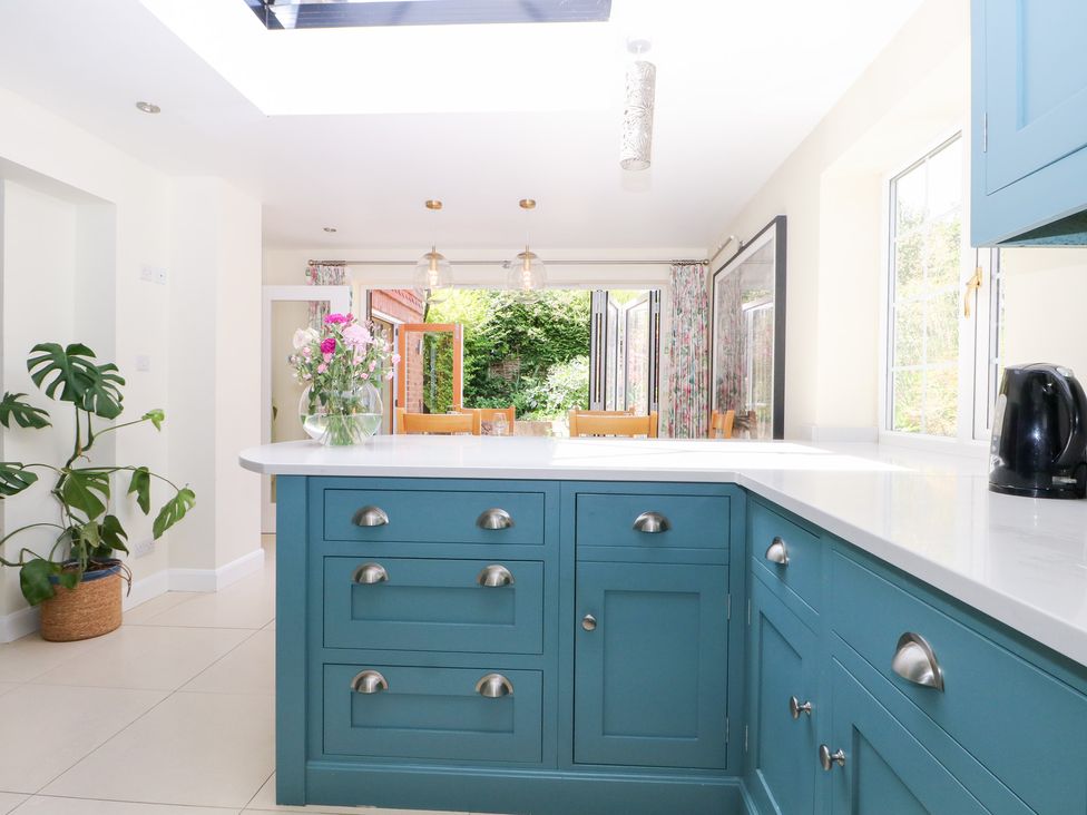 A kitchen with a kitchen island and a dining area at Cherry Garden Cottage Sandhurst