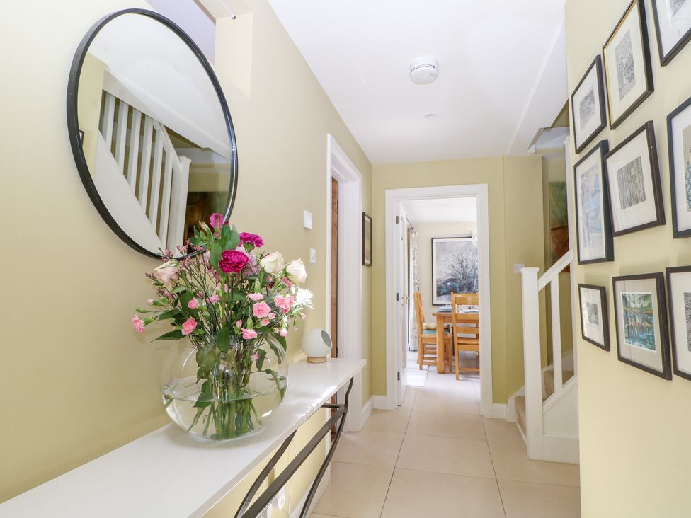 A hallway with flowers in a vase and a mirror at Cherry Garden Cottage Sandhurst