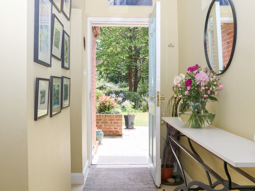 A hallway with a table and flowers at Cherry Garden Cottage in Sandhurst