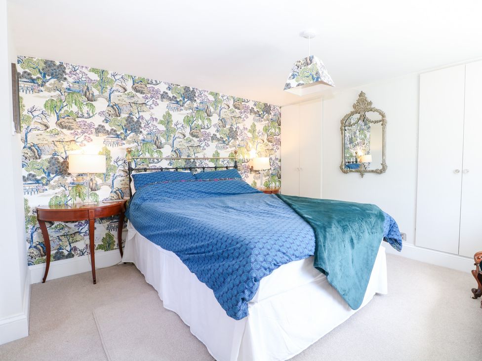 A bedroom with a bed and a mirror at Cherry Garden Cottage in Sandhurst