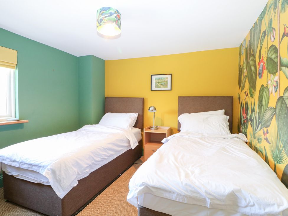 A bedroom with two beds and a bedside table at Cherry Garden Cottage Sandhurst