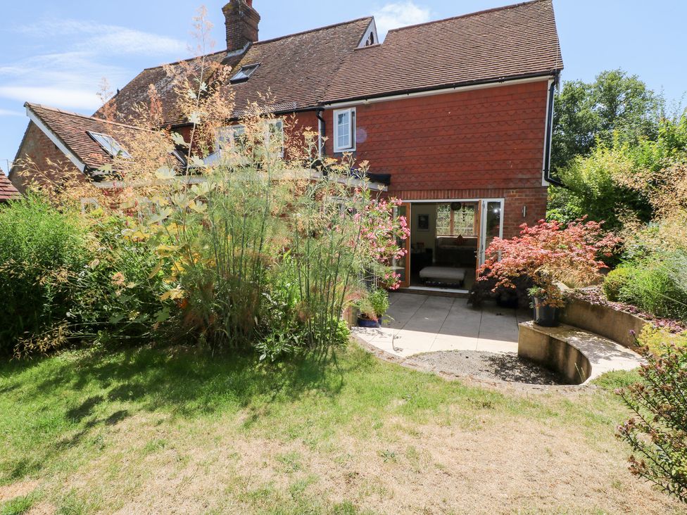 A garden with plants and a house at Cherry Garden Cottage in Sandhurst
