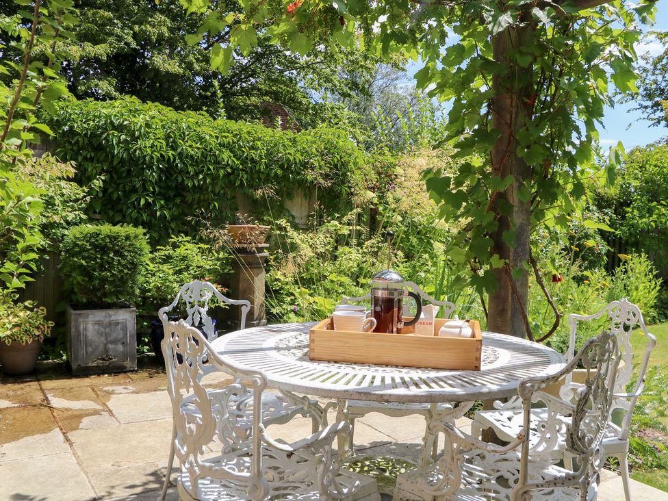 A garden with a table and chairs set up with a French press at Cherry Garden Cottage Sandhurst