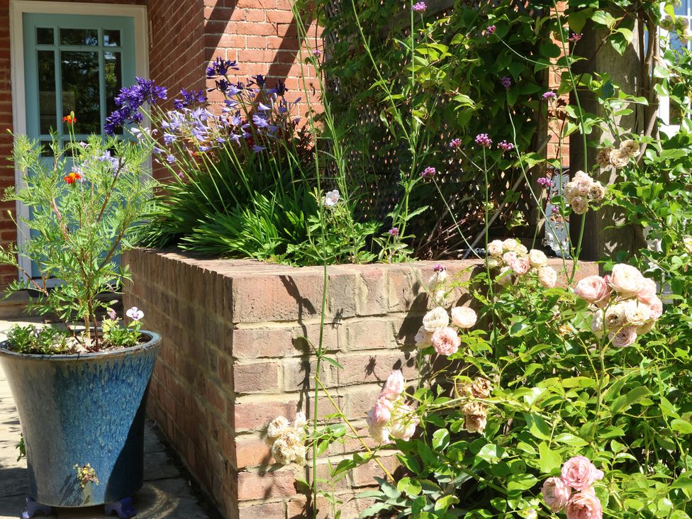 A garden with flowering plants and a brick wall at Cherry Garden Cottage in Sandhurst