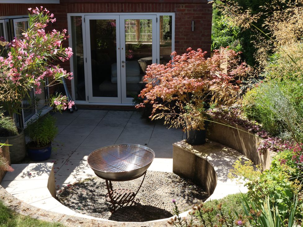 A garden with a barbecue and flowering plants at Cherry Garden Cottage, Sandhurst