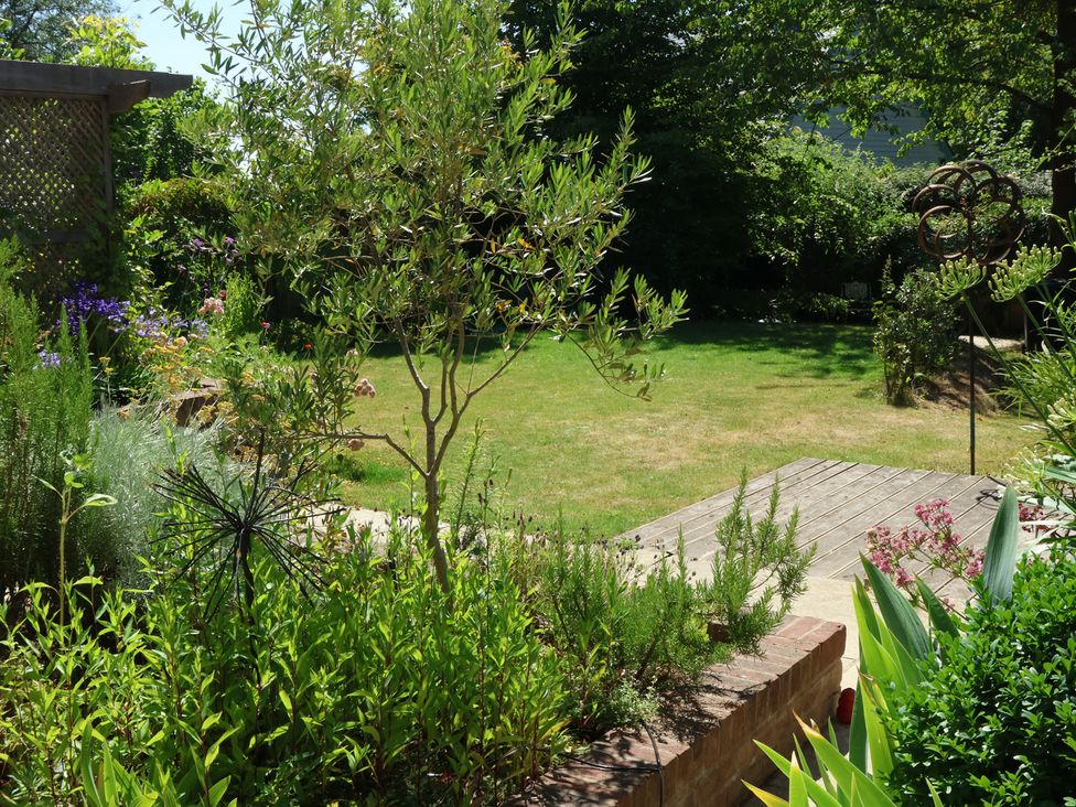 A garden with grassy area and wooden deck at Cherry Garden Cottage in Sandhurst