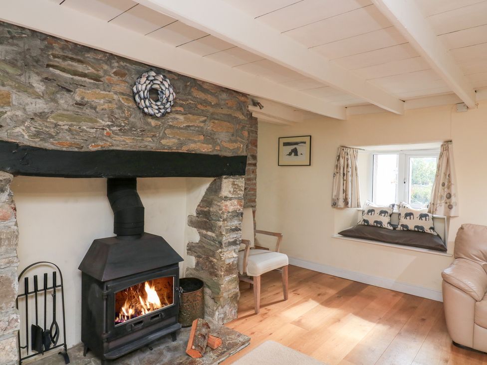 A living room with a wood stove and a window seat at Wayside near Kingsbridge