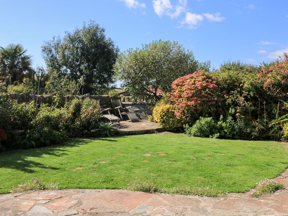 A garden with grass, flowers, trees and a patio at Wayside near Kingsbridge