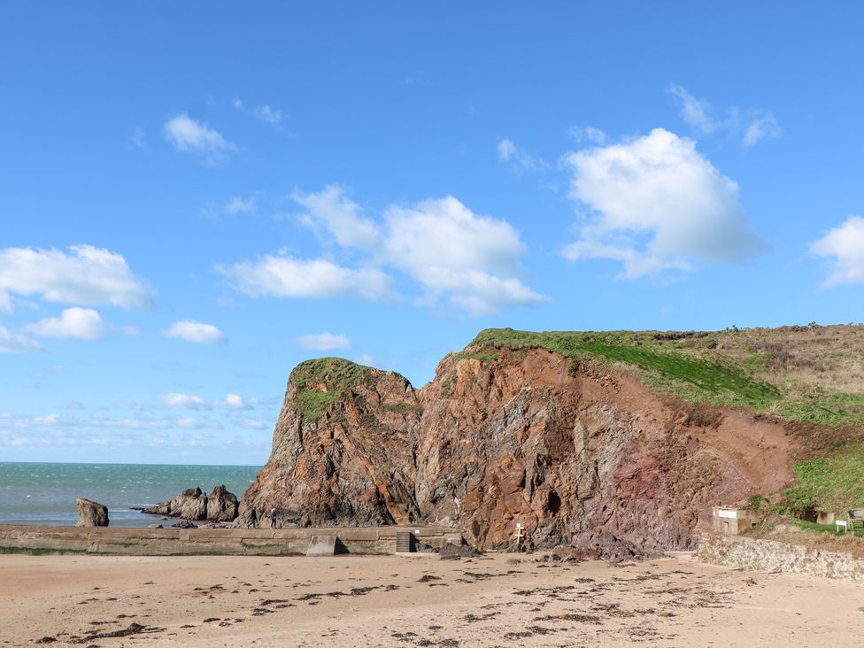 A beach with a cliff and ocean in the background at Wayside near Kingsbridge
