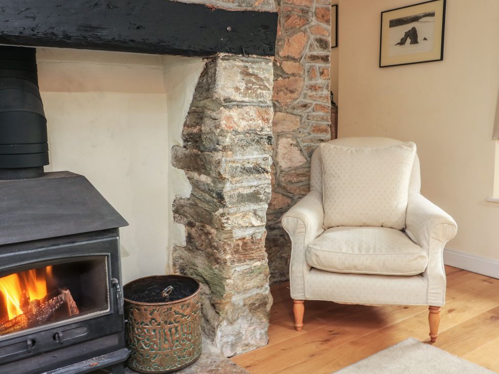 A living room with a fireplace and an armchair at Wayside near Kingsbridge