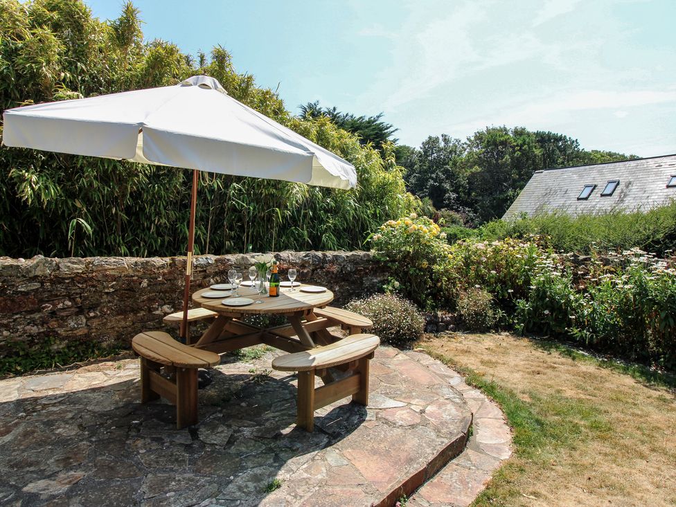 A table and chairs under an umbrella in the garden at Wayside near Kingsbridge