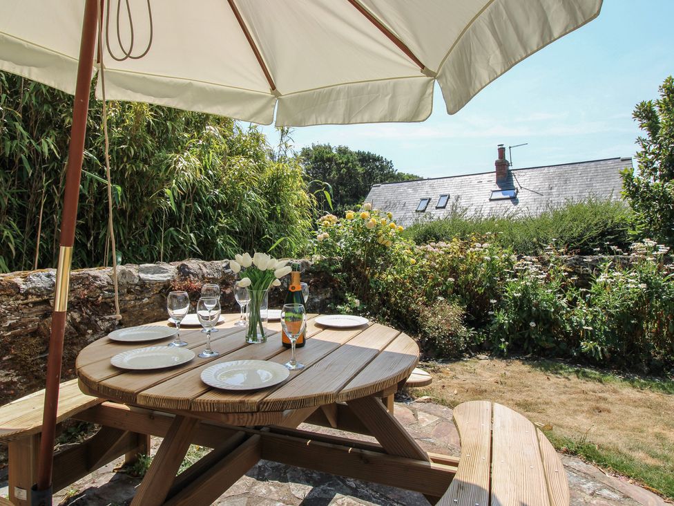A table with glasses and a bottle under an umbrella at Wayside near Kingsbridge