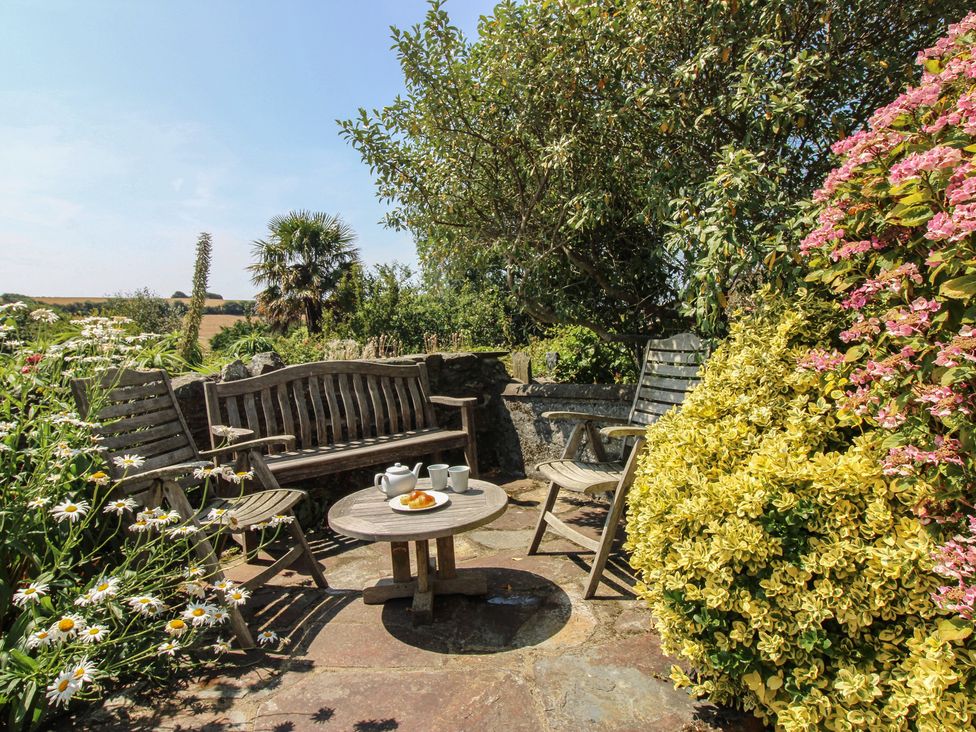 A garden seating area with wooden furniture and flowers at Wayside near Kingsbridge