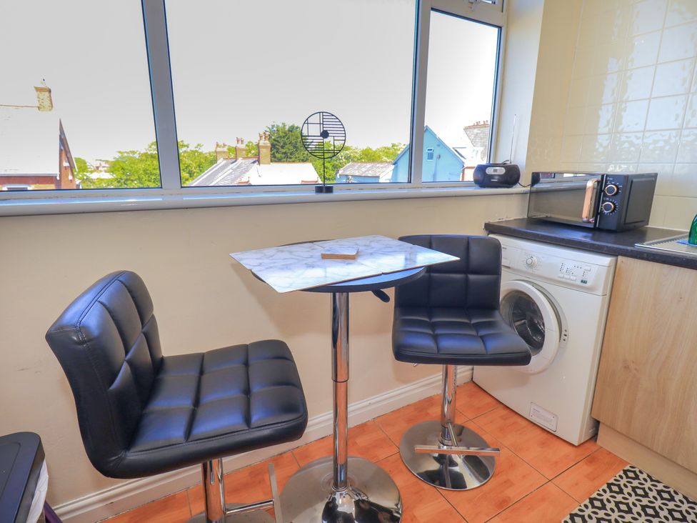 A kitchen with a table and stools and windows at The Nest in Lytham St. Annes