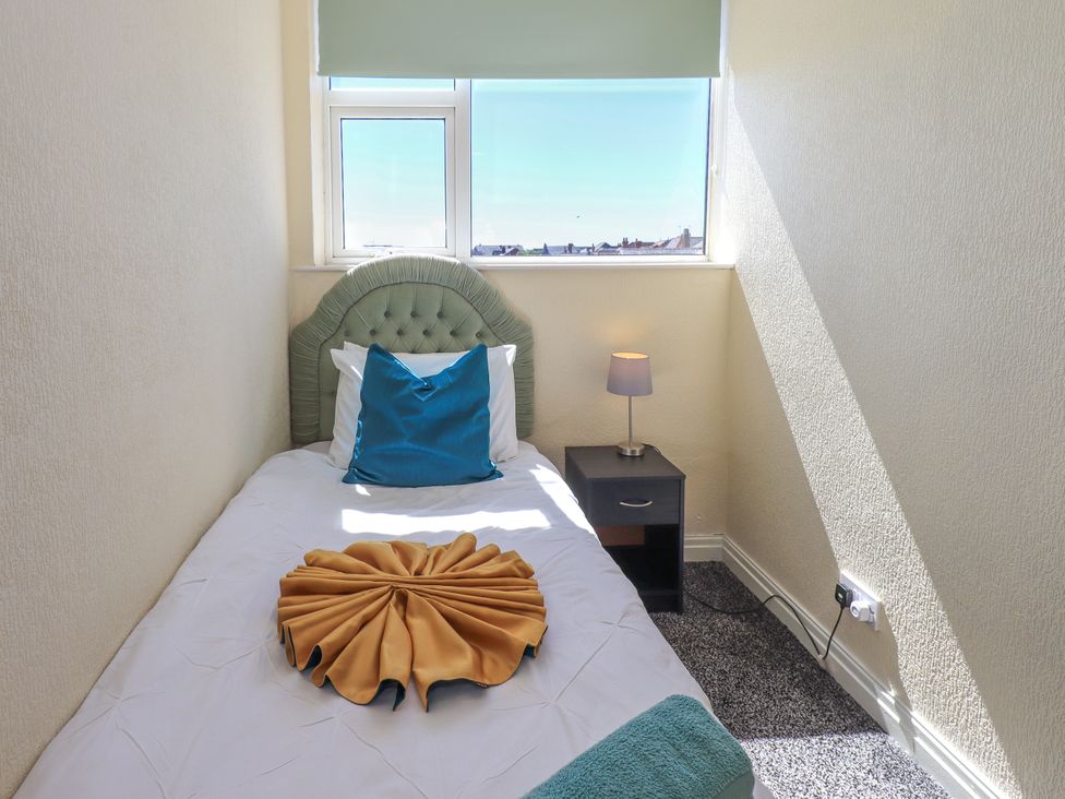 A bedroom with a single bed and a lamp on a nightstand at The Nest in Lytham St. Annes