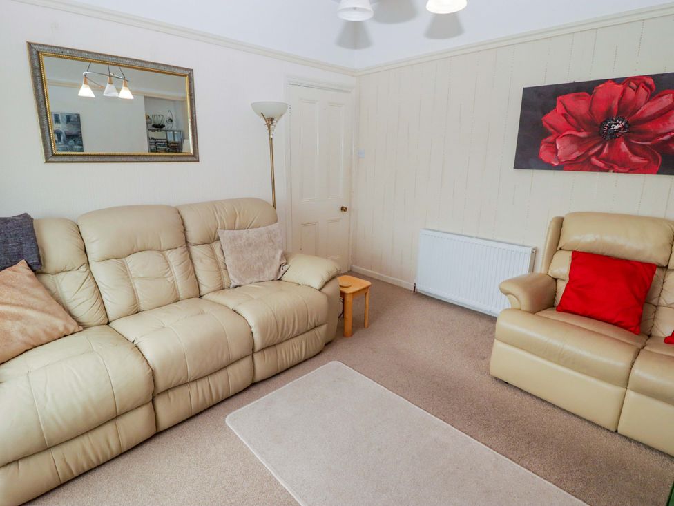 A living room with a sofa and armchair at Gwylan Maisonette in Tenby