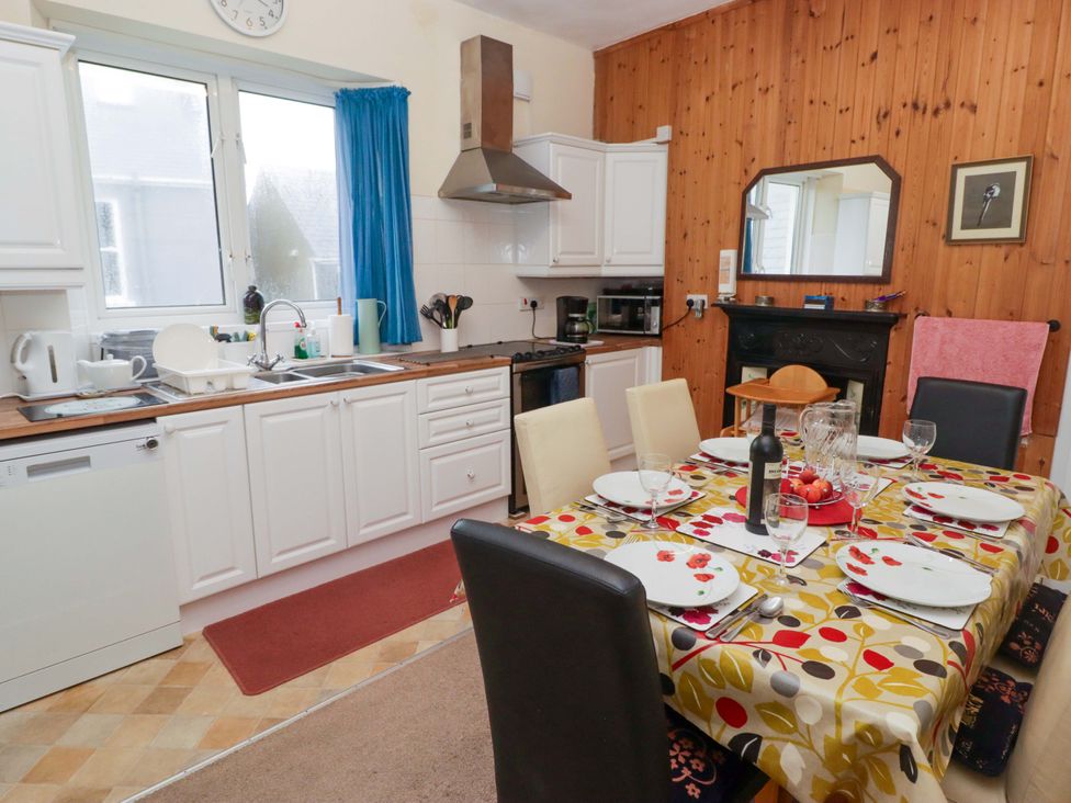 A kitchen with a dining area featuring a table and chairs at Gwylan Maisonette Tenby