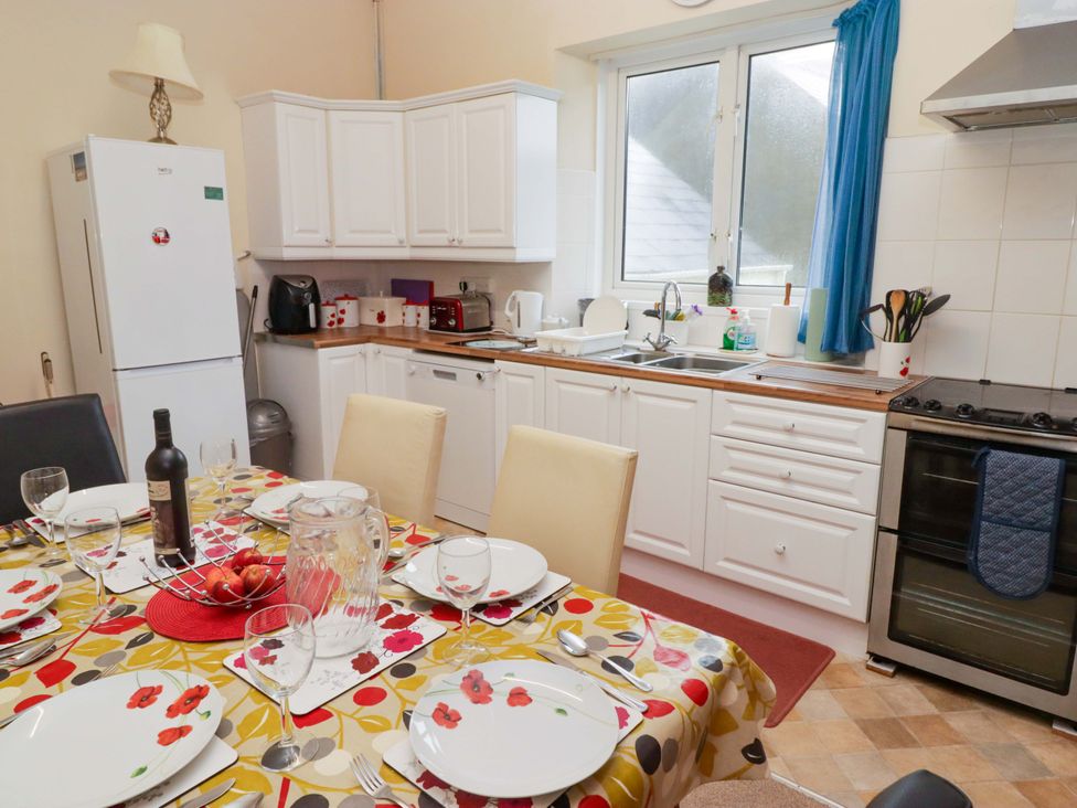 A kitchen with a dining area and appliances at Gwylan Maisonette in Tenby