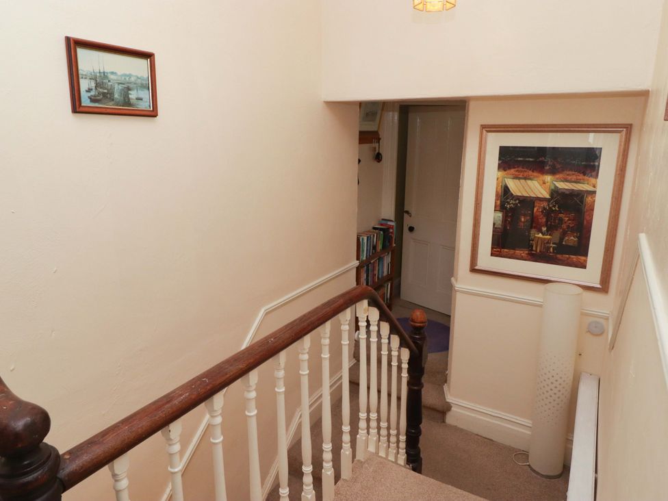 A staircase with a painting on the wall at Gwylan Maisonette in Tenby