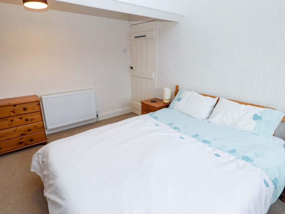 A bedroom with a bed and dresser at Gwylan Maisonette in Tenby